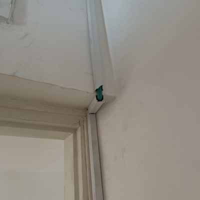 כבל חשמל ירוק בתוך תעלה על קיר לבן