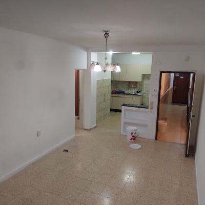 קיר צבוע בלבן עם דלי צבע ומגש על הרצפה