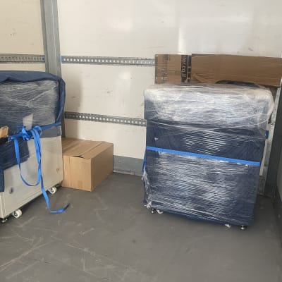 רהיטים עטופים בניילון וקשורים ברצועות בתוך משאית הובלה