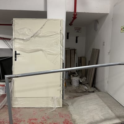 דלת עטופה בניילון במבנה תעשייתי עם צינורות אדומים