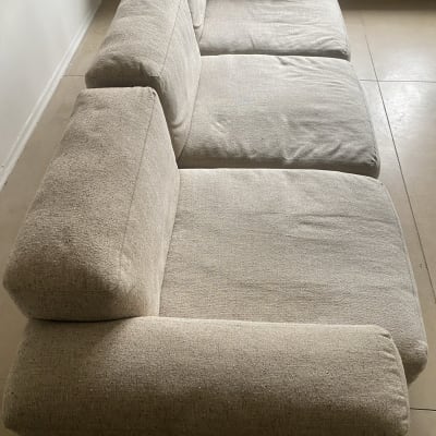 ספה בהירה עם שלושה מושבים, ללא כתמים נראים לעין.