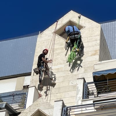 שני עובדים בגובה עם ציוד טיפוס על קיר בניין