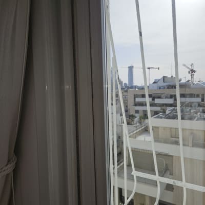 חלון עם תריסים פתוחים ונוף עירוני ברקע