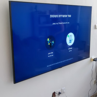 טלוויזיה תלויה על הקיר עם כבלים חשמליים גלויים