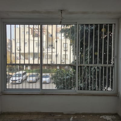 חלון אלומיניום עם סורגים מול בניין מגורים