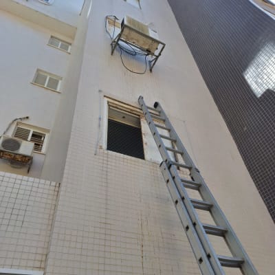 סולם מתכת נשען על קיר בניין ליד חלון פתוח