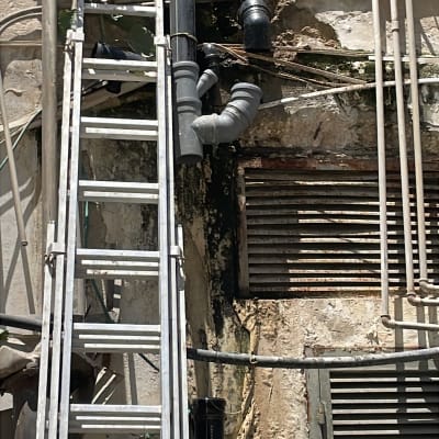 סולם ליד קיר עם צינורות ועבודות גובה
