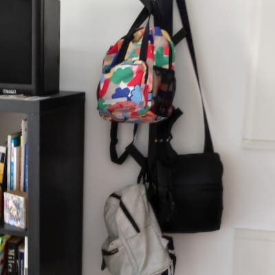 מתלה קיר שחור עם תיקים תלויים עליו