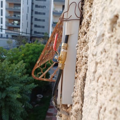 שסתום גז עם ידית אדומה על קיר חיצוני