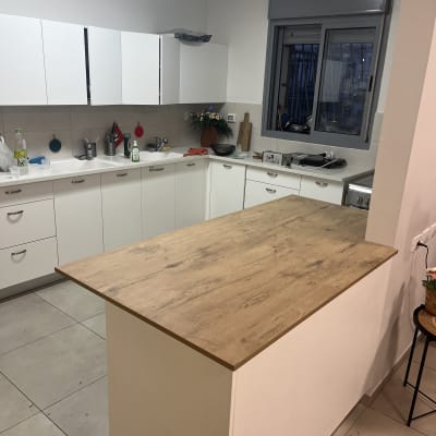 מטבח עם ארונות לבנים ומשטח עבודה מעץ