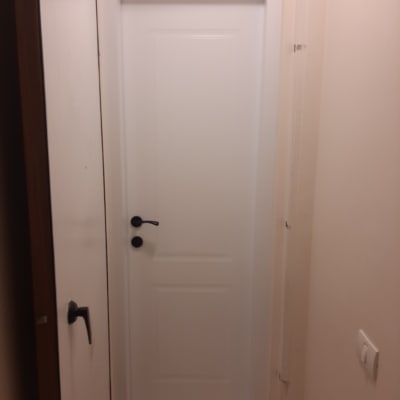 דלת לבנה עם ידית שחורה במסגרת עץ