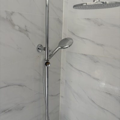 ראש מקלחת ומוט במקלחת עם אריחי שיש