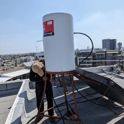 דוד שמש על גג עם אדם מבצע תחזוקה