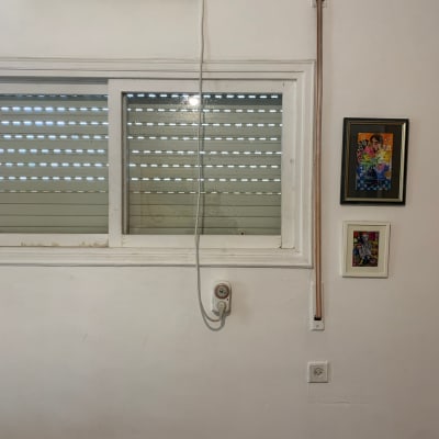 מזגן על קיר עם חלון ותריסים סגורים