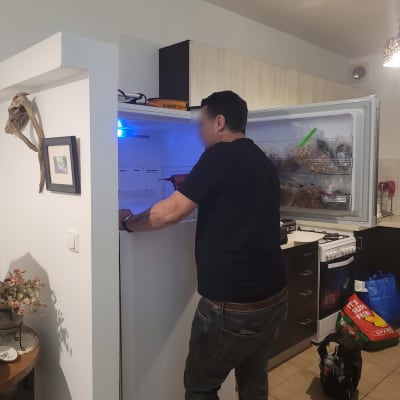 אדם עובד על מקרר פתוח במטבח ביתי