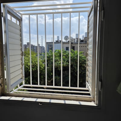 חלון פתוח עם סורגים ונוף חיצוני