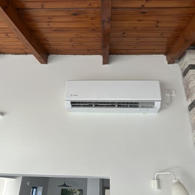 מזגן מותקן על קיר לבן מתחת לתקרה מעץ