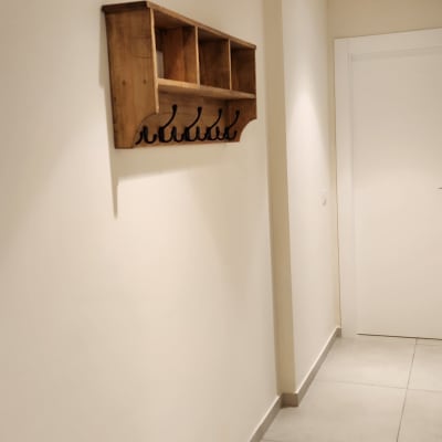 מדף עץ עם ווים לתלייה על קיר לבן