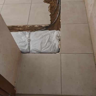 תיקון רצפה עם אריחים שבורים וצינורות חשופים