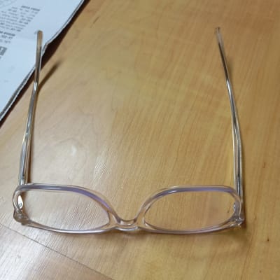 משקפיים שקופים על שולחן עץ ליד דף נייר