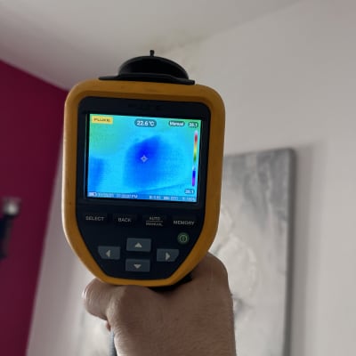 מד חום אינפרא אדום מציג טמפרטורה על קיר