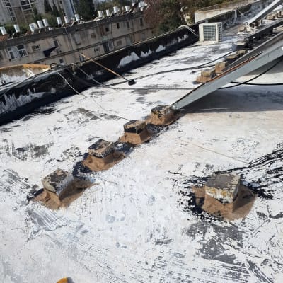 גג עם חומרי איטום, בלוקים וצבע לבן