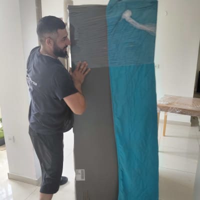 אדם מזיז מזרן עטוף בבית