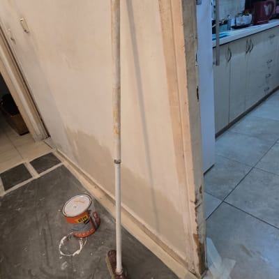 מקל צבע ודלי צבע על רצפה מכוסה בניילון