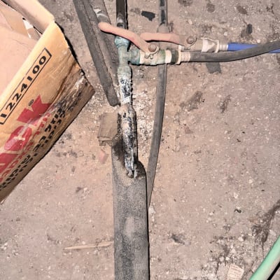 צינור עם ברז מתכת וחיבורים שונים על רצפה מאובקת