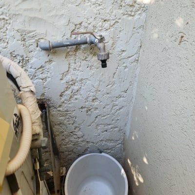 ברז מים ודלי לבן על רקע קיר טיח