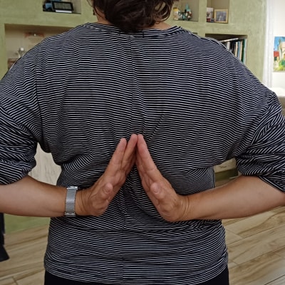 אדם מבצע תרגיל פיזיותרפיה עם ידיים מאחורי הגב