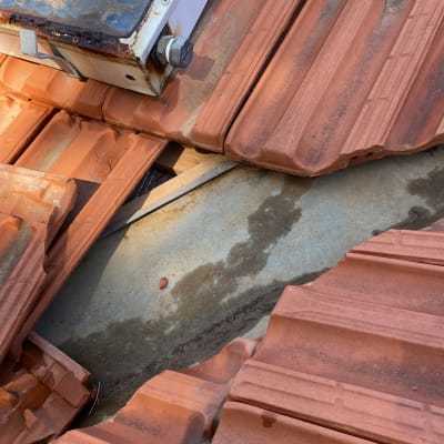 רעפים שבורים על גג עם לוח מתכת חשוף