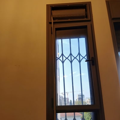 חלון עם תריס גלילה ונוף עירוני ברקע