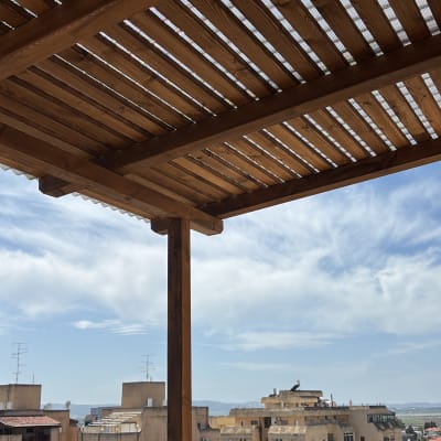 פרגולה מעץ עם קורות אופקיות על מרפסת