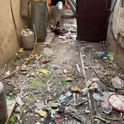 אדם עם כפפות כתומות מנקה פסולת בחצר