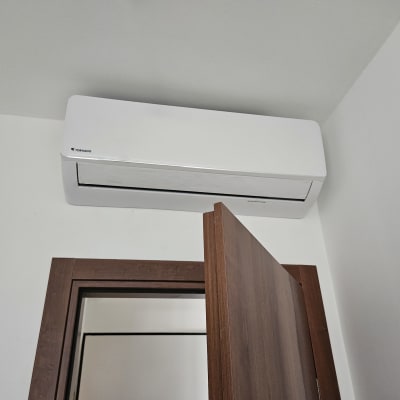 מזגן קיר לבן מותקן מעל דלת עץ