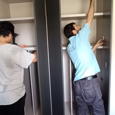 שני אנשים מתקינים ארון בגדים בחדר