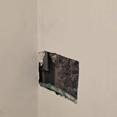 חור בקיר עם צינור ירוק גלוי