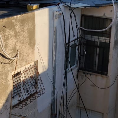 כבלים חשמליים תלויים על קיר חיצוני של בניין