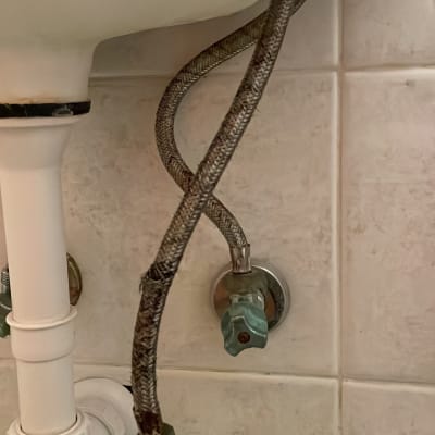 צינור מתכת מתחת לכיור עם ברז סגירה