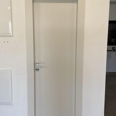 דלת לבנה עם ידית כסופה על קיר לבן