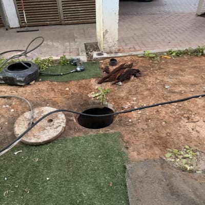 עבודת תחזוקה עם צינור וכלים ליד פתח ביוב