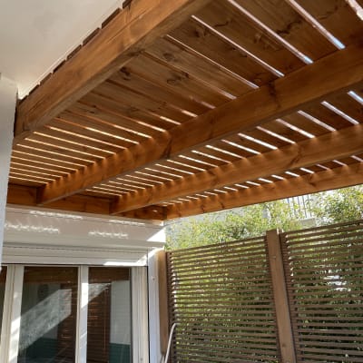 פרגולה מעץ מעל חלון עם תריסים מעץ