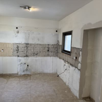קיר חשוף עם סימני שיפוץ וחלון קטן