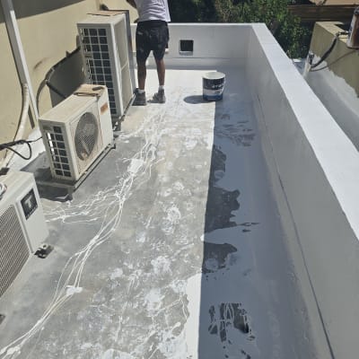 אדם מורח חומר איטום על גג עם מברשת