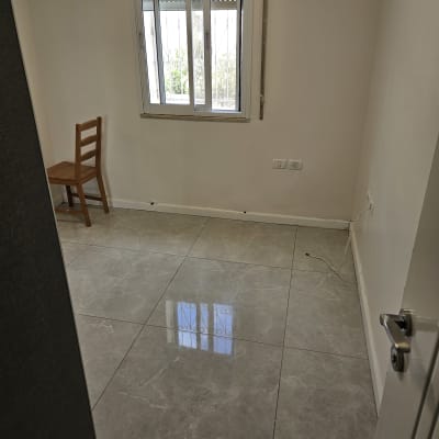 רצפה נקייה ומבריקה בחדר ריק עם חלון וכיסא עץ