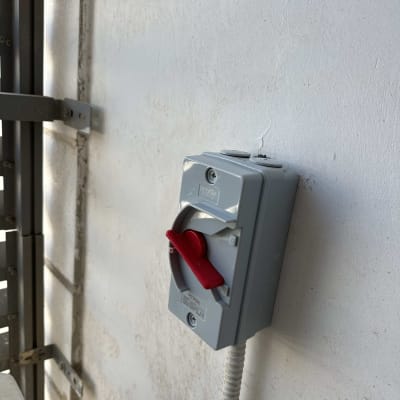 מתג חשמלי אפור עם ידית אדומה על קיר