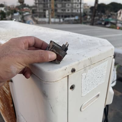 יד מחזיקה רכיב על מזגן על גג