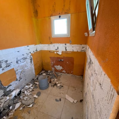 חדר בשיפוץ עם קירות כתומים ופסולת בנייה על הרצפה
