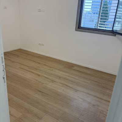 חדר ריק עם רצפת עץ נקייה וחלון פתוח